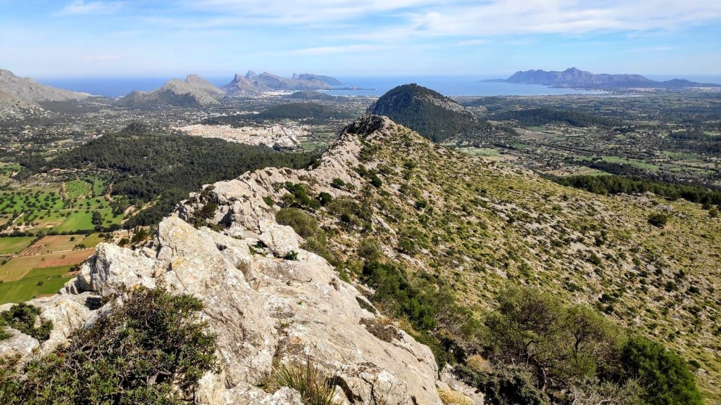 Serra de la Coma por la Regata de la Coma - Caminando por Mallorca Vista panorámica desde la cresta de la Serra de la Coma, mostrando valles verdes y la costa con el mar de fondo.