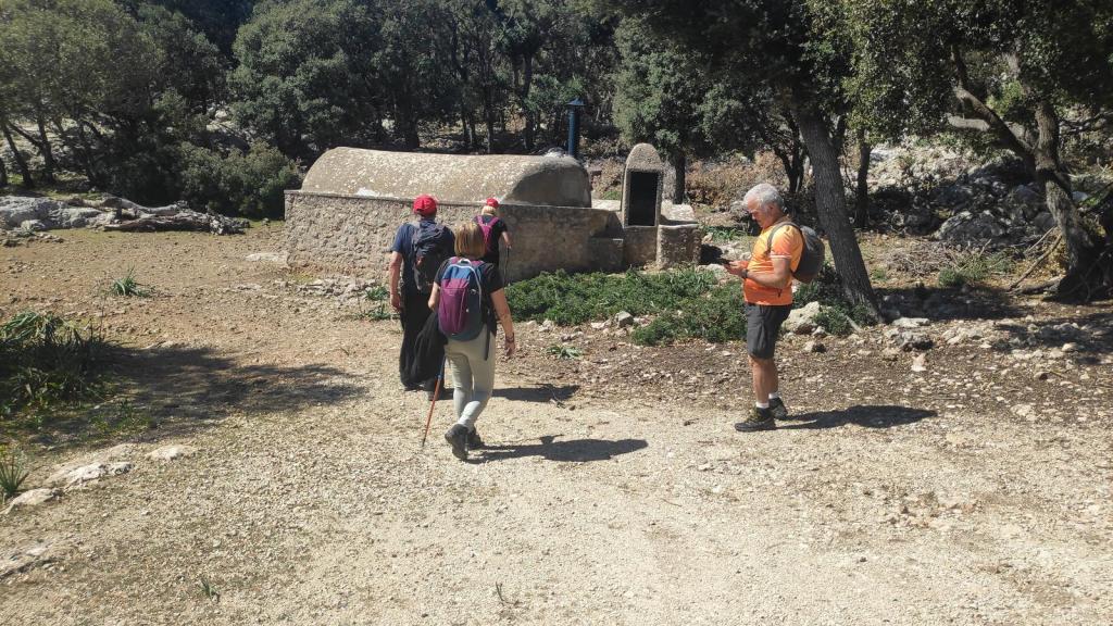 Grupo de excursionistas en un camino de tierra, con un antiguo horno de cal y vegetación de fondo.