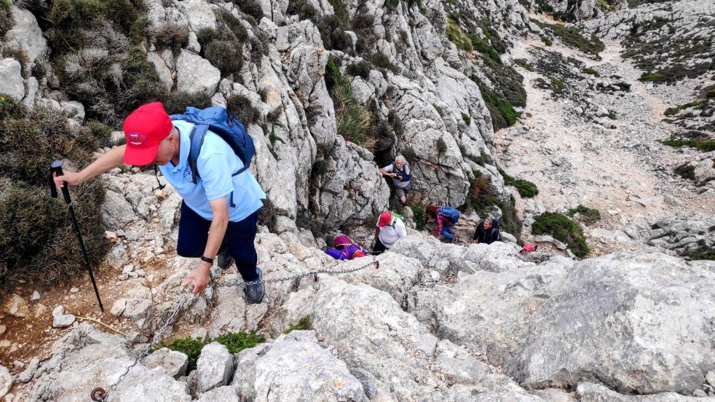 Grupo de personas escalando el Pas des Pedregaret, utilizando una cadena de seguridad en la ruta hacia el Puig Tomir.