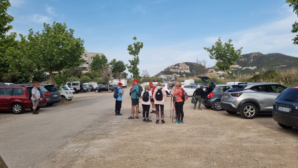Grupo de excursionistas en el aparcamiento del Puerto de Andratx, rodeados de árboles y coches, listos para comenzar la ruta Sa Talaia.