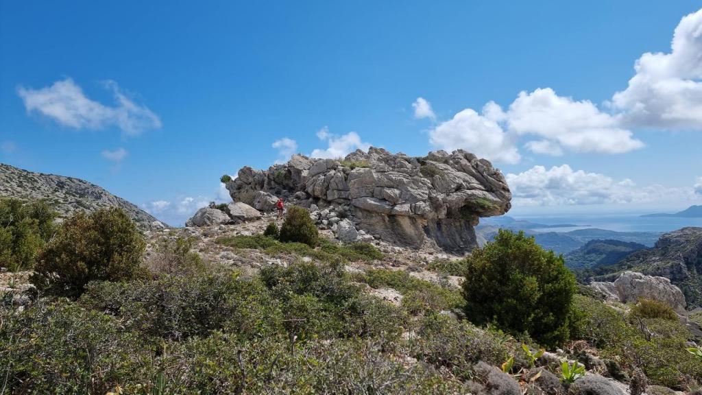 Vista panorámica dell Paraigo, mostrando formaciones rocosas y vegetación de montaña bajo un cielo azul con nubes.