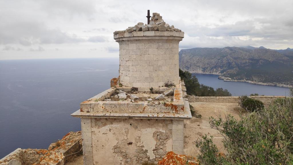 Vista del Far de na Pòpia en la isla de Sa Dragonera, con el mar al fondo y montañas en el horizonte. La estructura del faro muestra signos de deterioro.