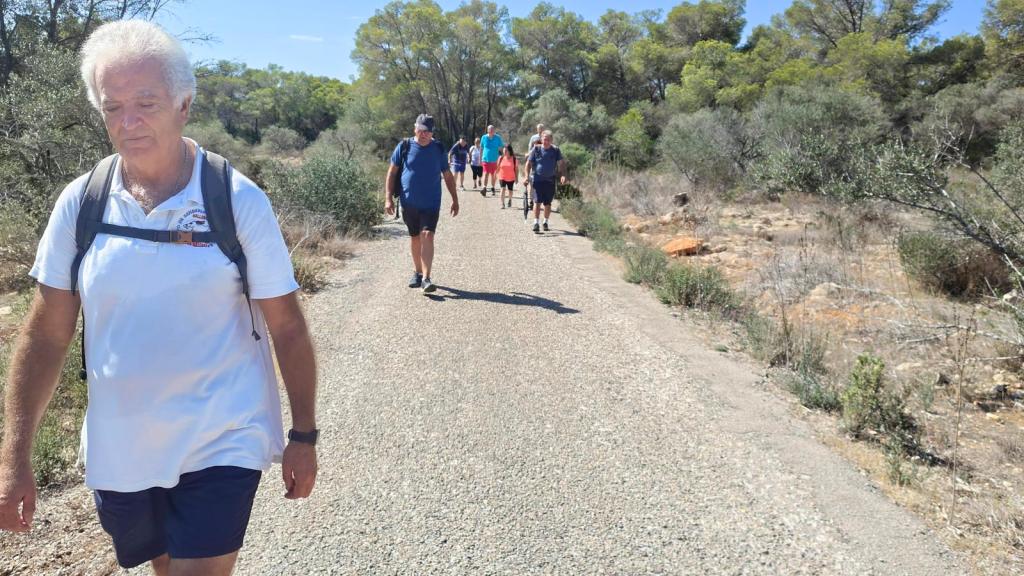 Punta del Toro y Cala Rafeubetx - Caminando por Mallorca Grupo de personas caminando por un sendero rodeado de vegetación en la ruta Punta del Toro y Cala Rafeubetx.