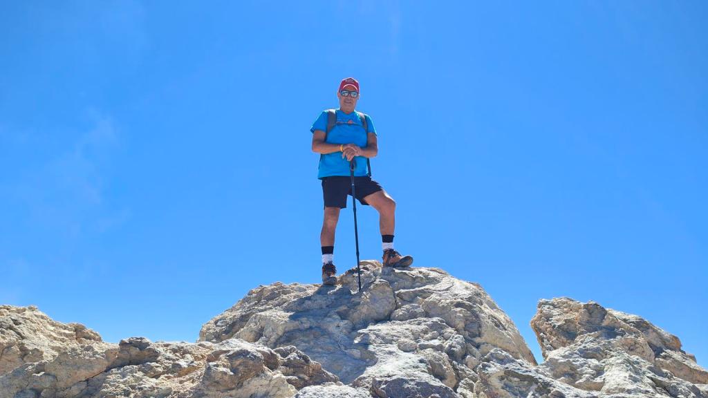 Persona de pie sobre una roca en la cima del Teide, con fondo de cielo azul claro.