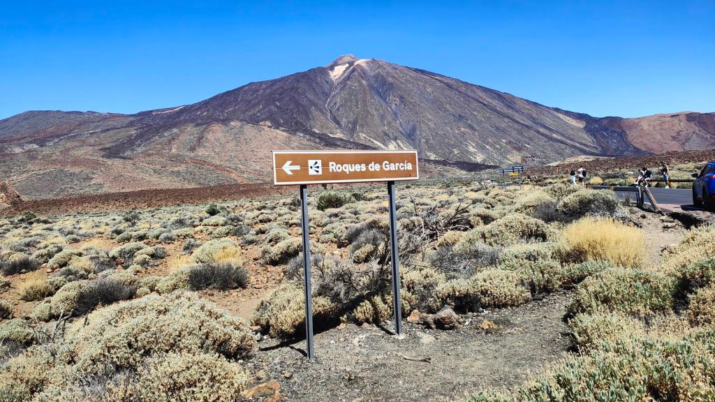 Señal indicando la dirección hacia los Roques de García, con el volcán Teide de fondo y un paisaje de vegetación árida.