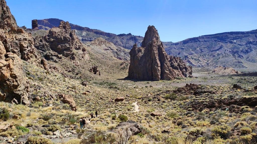 Vista panorámica de la ruta 'Los Roques de García' con formaciones rocosas y senderistas en un paisaje árido de Tenerife.