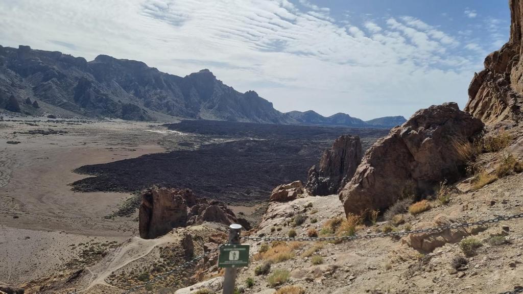 Vista panorámica de la ruta 'Los Roques de García' en el Parque Nacional del Teide, con formaciones rocosas y un extenso llano de lava.
