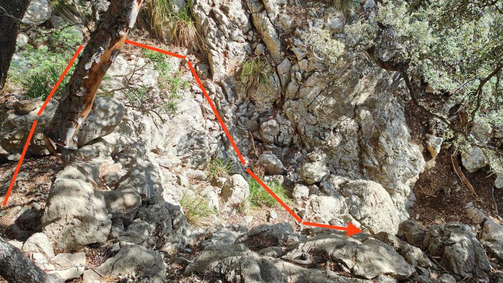 Sendero rocoso en la ruta 'Pas des Gat' con indicaciones en color rojo y vegetación circundante.