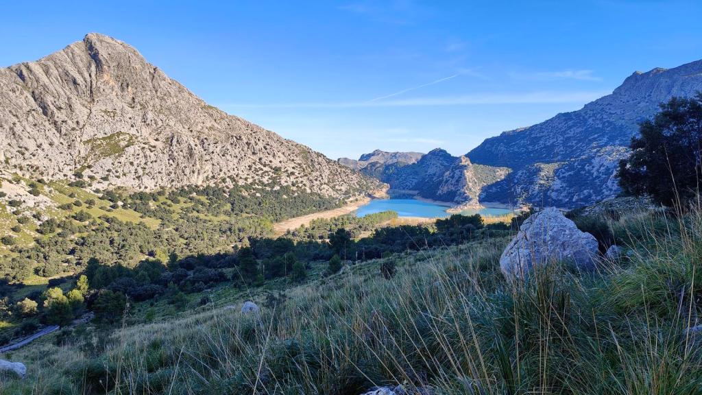 Vista panorámica del embalse de Gorg Blau y las montañas circundantes, con vegetación abundante en primer plano.