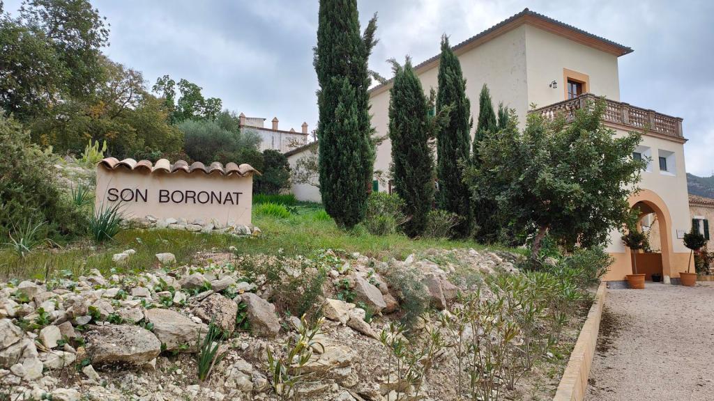 Son Boronat desde Calviá - Caminando por Mallorca Entrada a la finca Son Boronat, con un letrero visible y vegetación alrededor, mostrando la arquitectura del edificio y el ambiente rural.