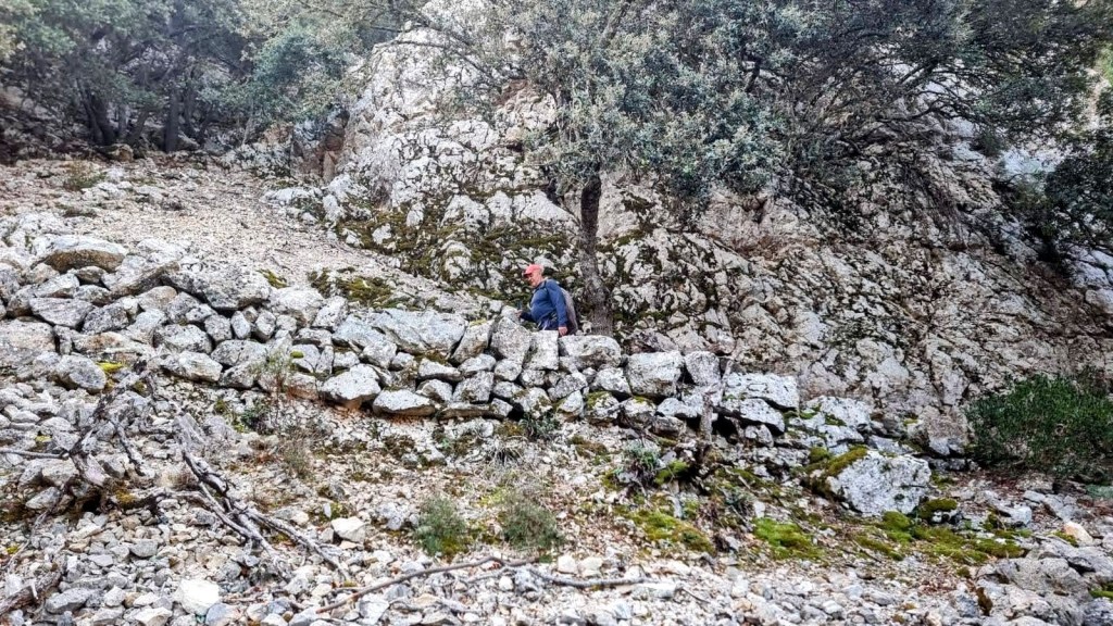 Un senderista caminando por el Camí des Caragol, en un entorno natural montañoso.