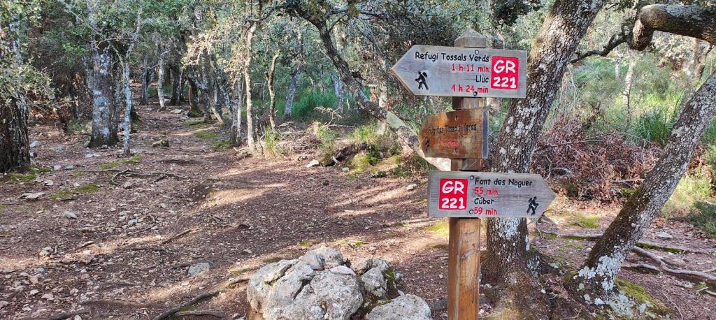 Señales de dirección en el Coll des Coloms que indican rutas hacia el Refugio Tossals Verds y Font des Noguer con información de tiempos de caminata.