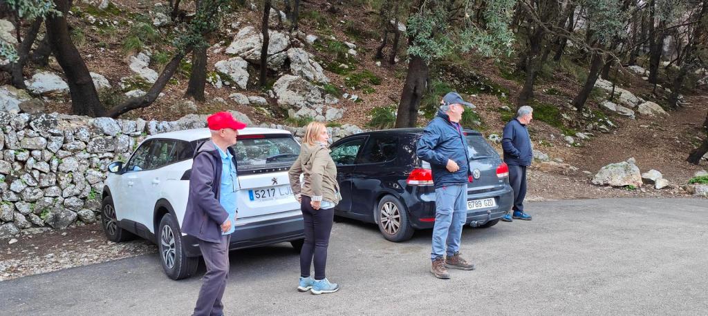 Grupo de personas en un aparcamiento al inicio de la ruta Puig de Na Fátima, rodeados de árboles y rocas.