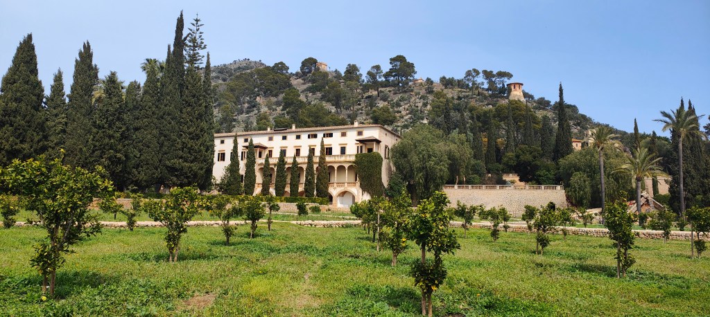 Vista panorámica de la Finca de Raixa, rodeada de jardines y montañas en Mallorca, con árboles y un paisaje verde.