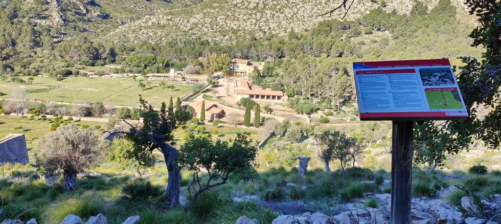 Moleta de Galatzó por Ses Planes - Caminando por Mallorca Vista panorámica de la finca pública de Galatzó con un cartel informativo sobre la ruta 'Moleta de Galatzó por Ses Planes' en primer plano.