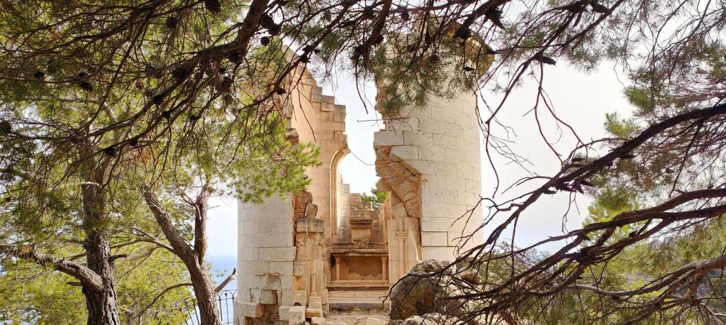 Miradores del Archiduque 2 - Caminando por Mallorca Ruinas del Mirador de sa Capellau, na estructura arquitectónica con arcos, rodeadas de árboles en la ruta "Miradores del Archiduque 2" en la Sierra de Tramontana, Mallorca.