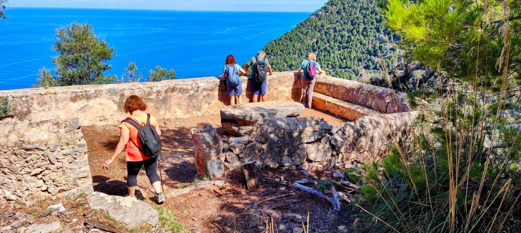 Grupo de excursionistas explorando el Mirador des Pi, con vistas al mar y acantilados de Valldemossa.