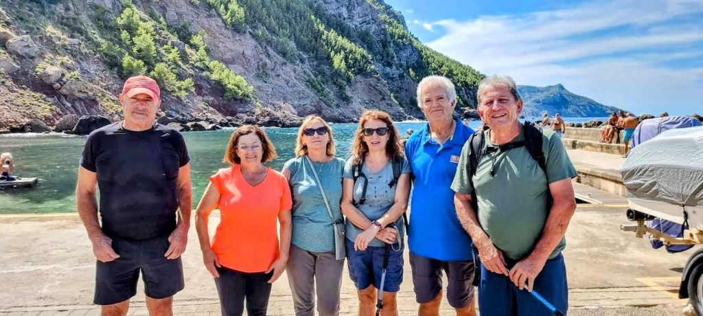Grupo de seis personas posando en el puerto de Valldemossa, con acantilados y mar de fondo.