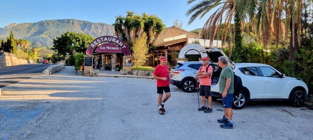 Grupo de senderistas en el aparcamiento del restaurante 'La Meson', al inicio de la ruta 'Mola de Son Termes-Puig del Colomer'. Al fondo, montañas y vegetación abundante.