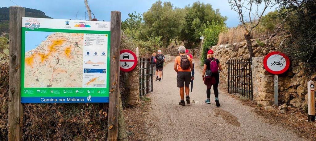 Fesa Costitxa-Font de la Coma desde Puigpunyent - Caminando por Mallorca Grupo de personas caminando por un sendero en Mallorca, con un mapa de la ruta y señales de no entrar en bicicleta.