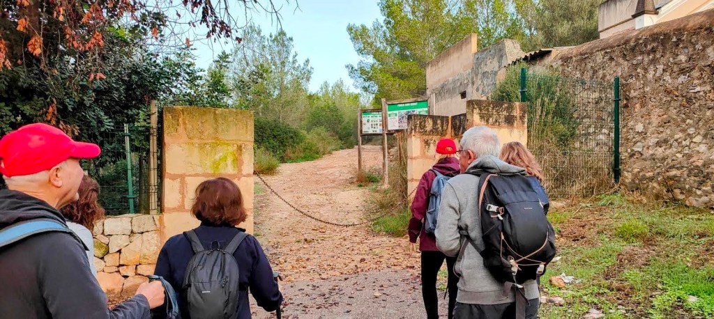 Grupo de personas iniciando una caminata por un sendero en la Serra de Son Marill, con un entorno natural y una entrada marcada con un cartel.