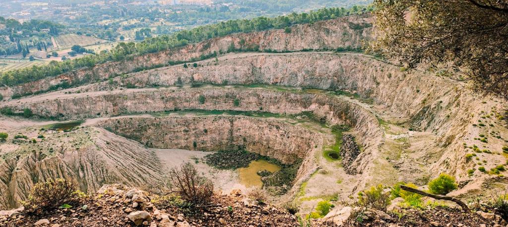 Vista panorámica de una antigua cantera con formaciones rocosas y vegetación en los alrededores, mostrando el paisaje de la Serra de Son Marill.