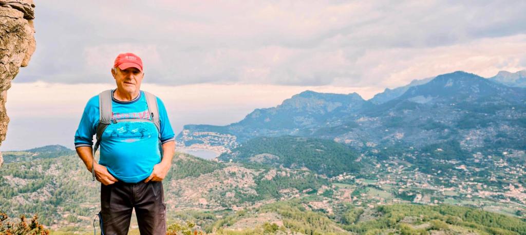 Hombre en una ruta de senderismo mirando hacia el valle de Sóller con montañas al fondo.