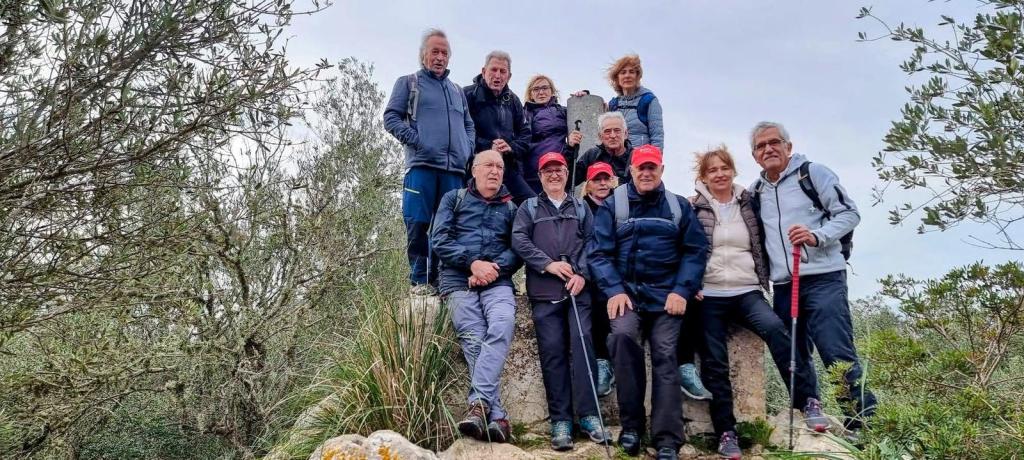 Grupo de personas posando en la cima del Puig de Bonany, rodeados de vegetación.
