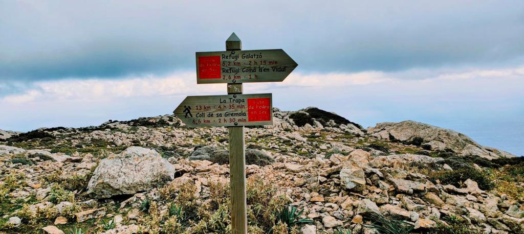 Señal de rutas en un área montañosa, mostrando direcciones hacia el Refugio Galatzó y Refugio Coma d'en Vidal, con indicaciones de distancias y tiempos de caminata.