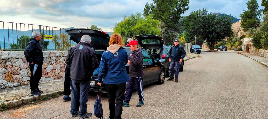 Grupo de personas preparándose para iniciar una ruta de senderismo cerca de Valldemossa, con un paisaje montañoso de fondo.