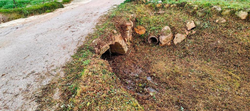 Vista de una zanja cerca de un camino, con restos de tierra y piedras a su alrededor.