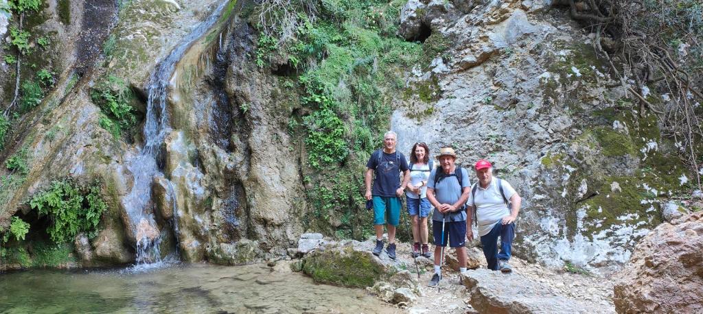 Font d’Es Verger desde Biniaraix - Caminando por Mallorca Grupo de personas posando frente a una cascada en un entorno natural con vegetación abundante.