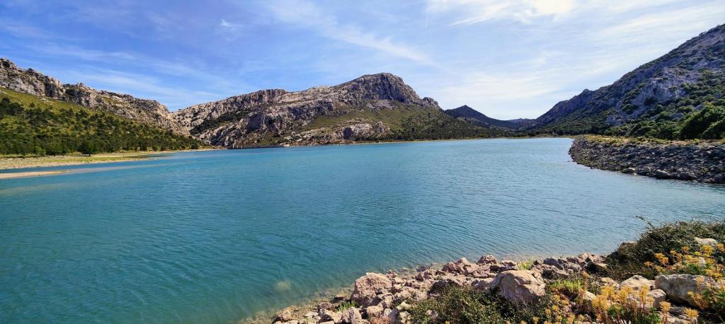 Vista del embalse de Cúber rodeado de montañas con aguas cristalinas reflejando el cielo claro.