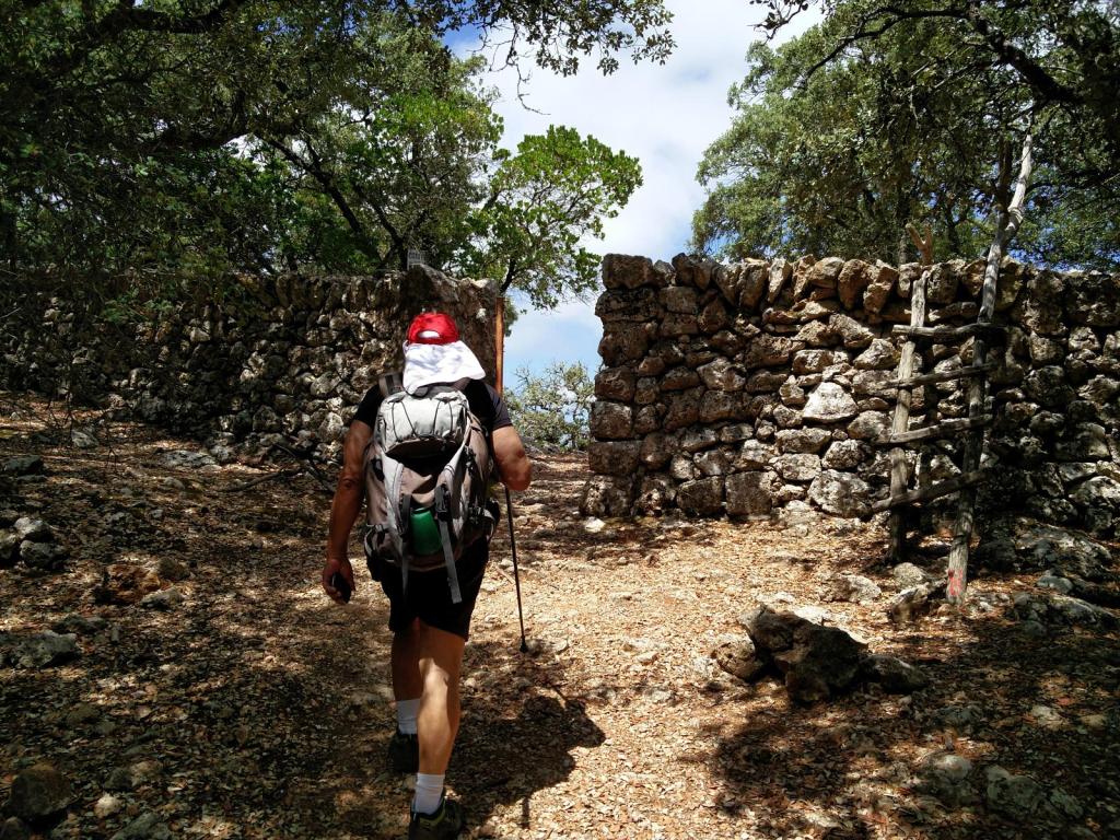 Senderista caminando hacia un portillo de piedra en el Coll de Estellencs