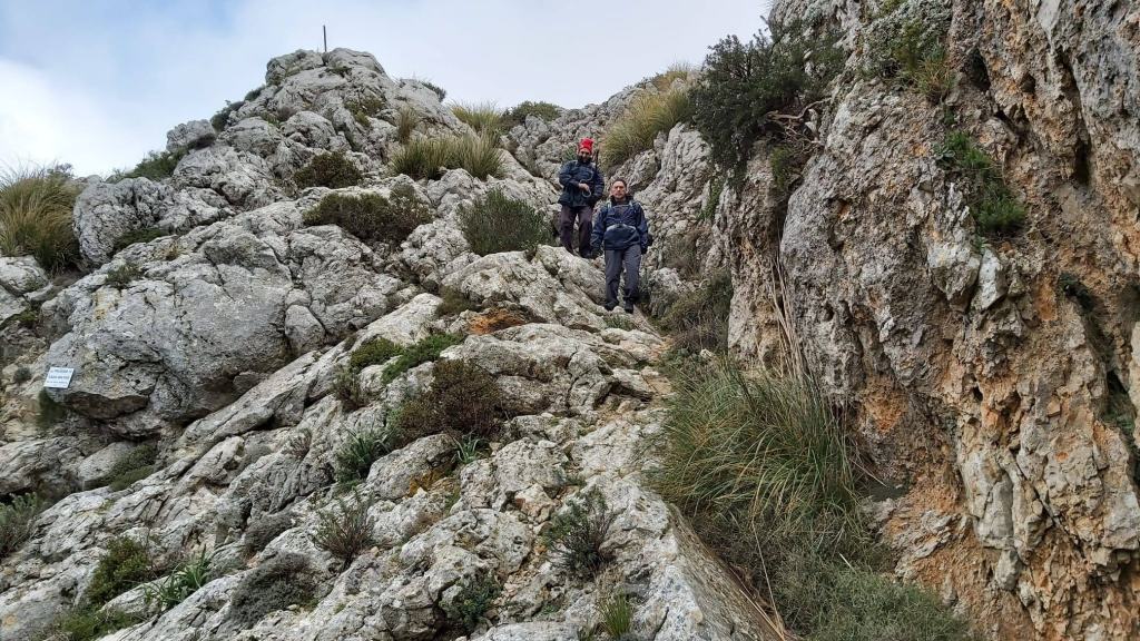 Grupo de excursionistas descendiendo por el Pas de n’ Agustí, rodeados de vegetación escasa y grandes rocas.