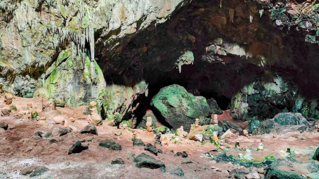 Vista del interior del Avenc de Son Pou, mostrando formaciones rocosas y estalagmitas en el suelo, en un entorno cavernoso con paredes irregulares y colores naturales.