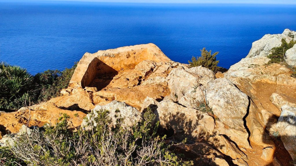 Vista desde del Mirador d’en Josep Sastre con rocas y vegetación en primer plano, mirando hacia el mar azul.