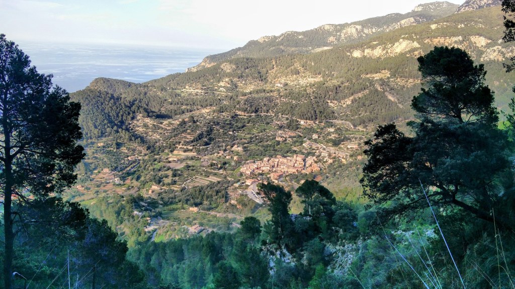 Vista panorámica del valle y el pueblo de Estellencs, con montañas y vegetación en el fondo.