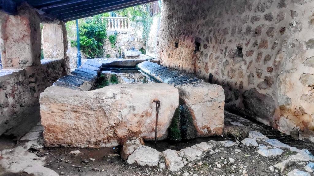 Imagen de los lavaderos públicos de Biniaraix, con un área de piedra y agua reflejando el entorno.