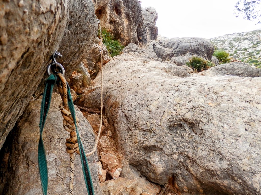 Vista cercana de una roca con un anclaje de escalada y una cuerda, en el Pas de sa Trapa.