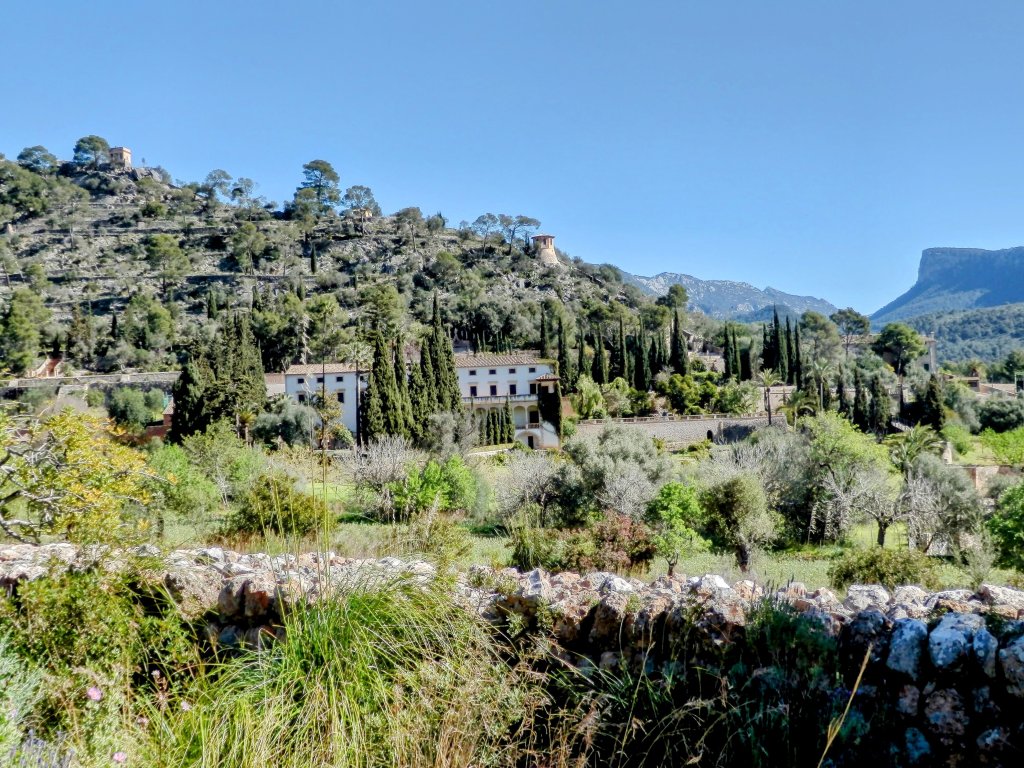 Vista panorámica de la finca Raixa en Mallorca, con edificios de estilo tradicional rodeados de vegetación y montañas al fondo.