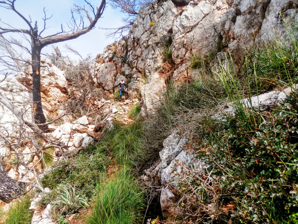 Sendero rocoso en la Mola de s'Esclop, con un caminante ascendiendo al Pas de s’Esteparet, también llamado Pas des Ponça