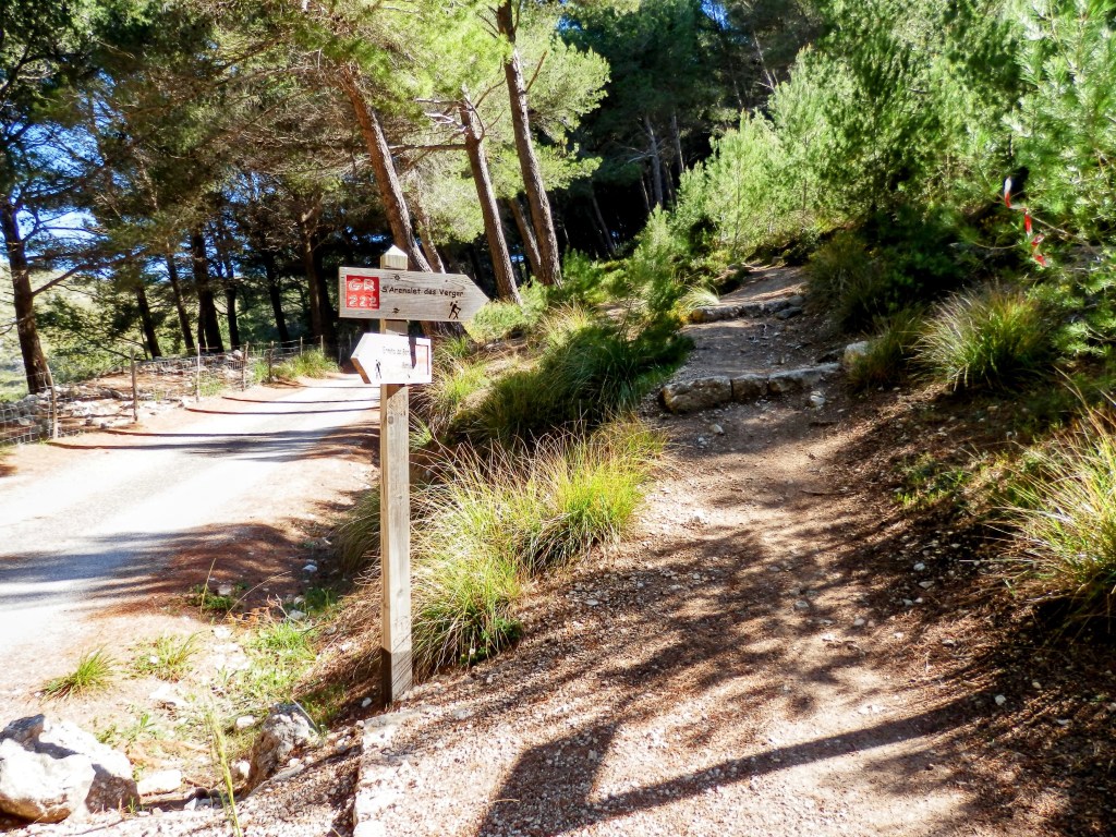 Señal de sendero indicando la dirección hacia s'Arenalet d'es Verger y camino de s'Esquena Llarga rodeada de vegetación en el Parque Natural de la Península de Llevant.