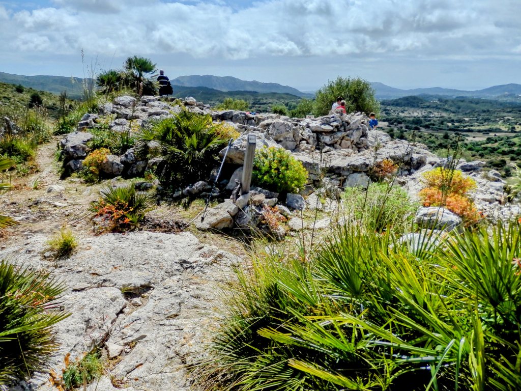 Vista del Talaiot del Puig Figuer, una torre prehistórica circular rodeada de vegetación, situada en un paisaje montañoso del Parque Natural de la Península de Llevant.