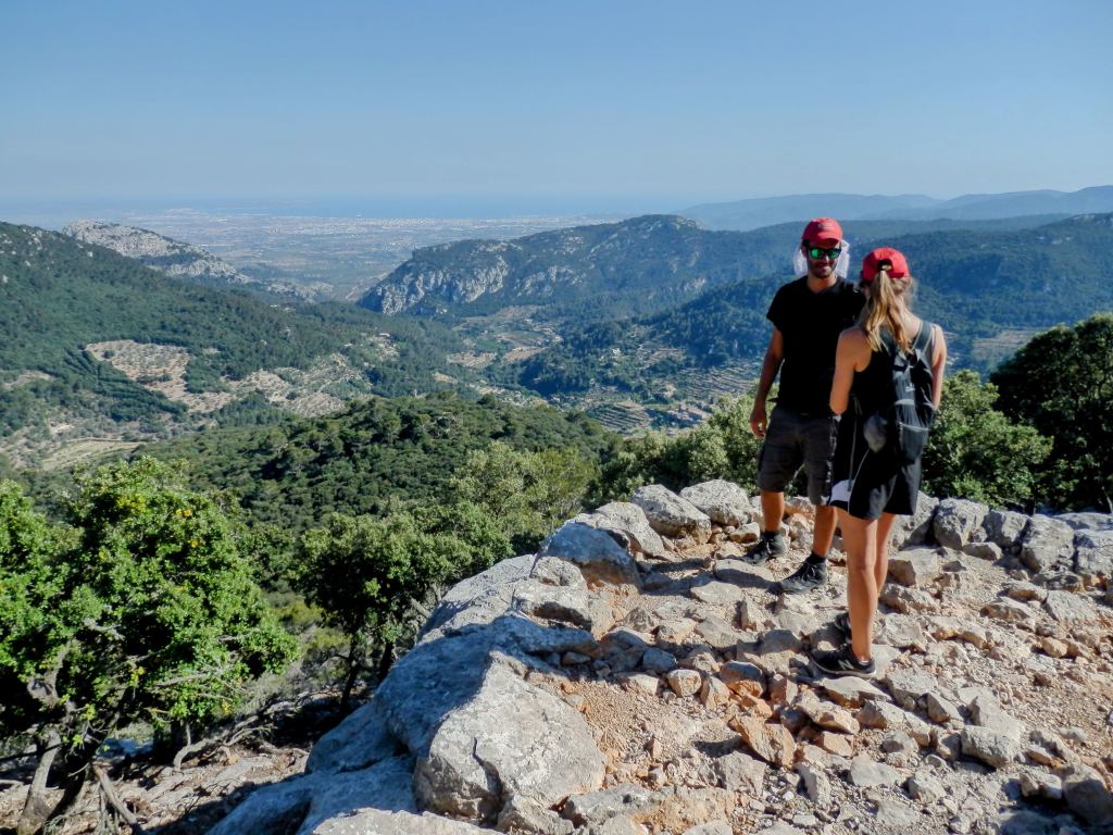 Dos personas en el Mirador de ses Basses disfrutando de vistas panorámicas de montañas y valles en Mallorca.