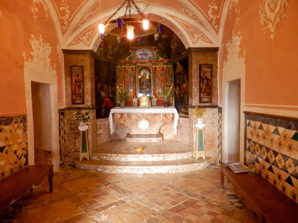 Interior de la Ermita de la Madre de Dèu del Refugi, con altar decorado y azulejos ornamentados en las paredes.