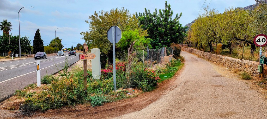 Intersección de caminos en Bunyola, con señalización de ruta y carretera, rodeada de vegetación y paisaje rural.