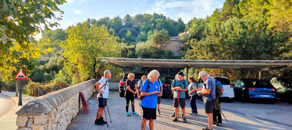 Grupo de senderistas preparándose para comenzar la ruta "Puig de Sa Creu desde Mancor de la Vall" en un aparcamiento rodeado de naturaleza.