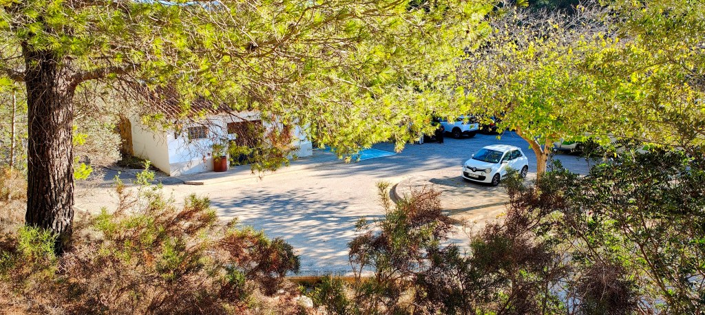 Vista del aparcamiento y un edificio rodeado de árboles en Cementerio de s'Arracó, Mallorca.
