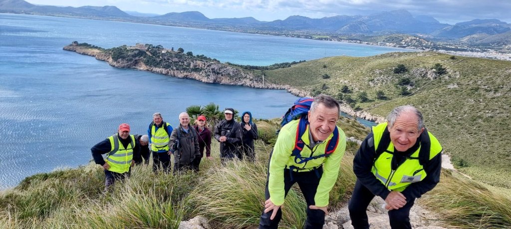 Grupo de personas en una caminata de senderismo en la cima del Puig Munt de Blat con vistas al mar y montañas al fondo.